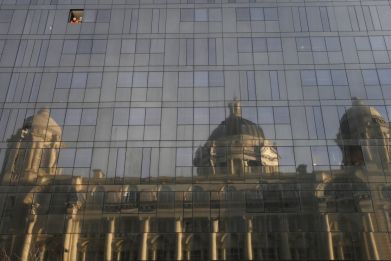Workmen look out of a window in the new Mann Island apartment development as the Port of Liverpool building is reflected in the glass, in Liverpool, northern England February 14, 2011.