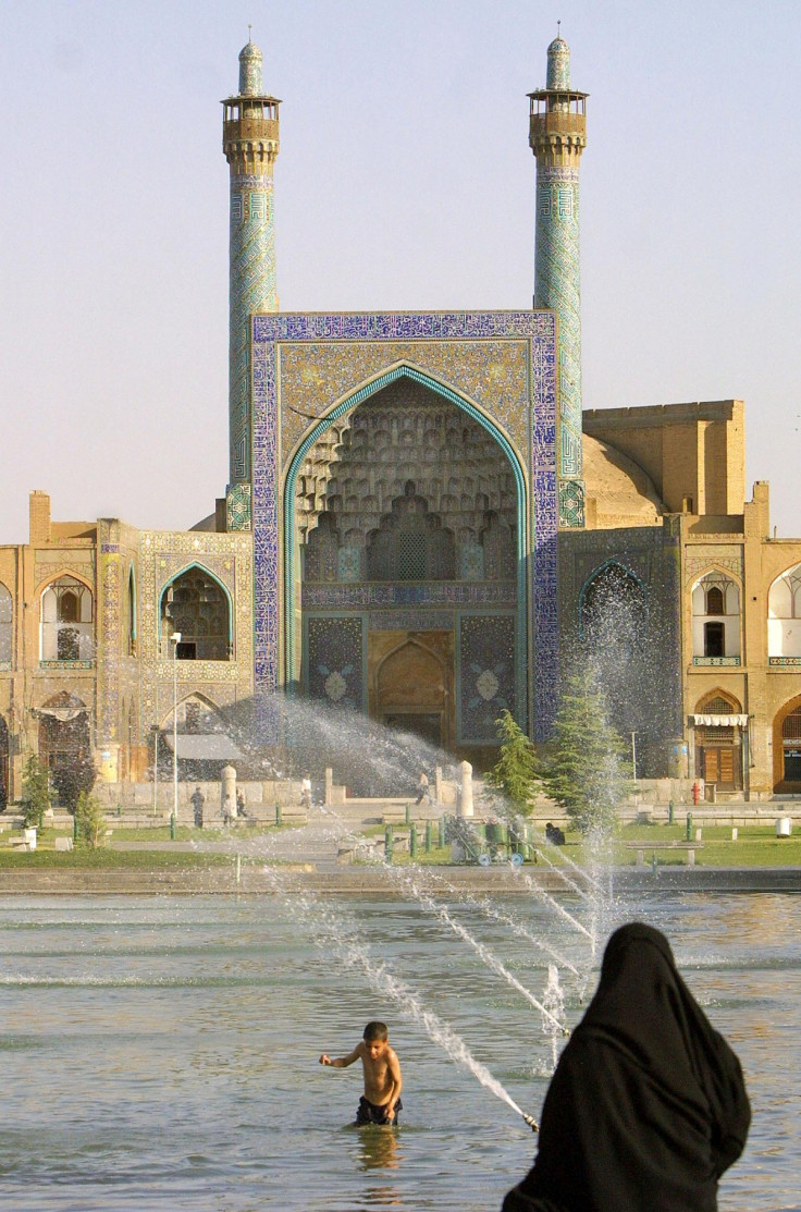 An Iranian woman looks at a boy swiming in the pool of Imam square (royal square) as the historic Imam mosque built in 1638 is seen in the background in Isfahan