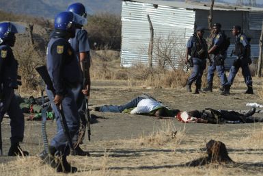 Police stand over the bodies of dead protesters in Marikana, 2012. (Getty)