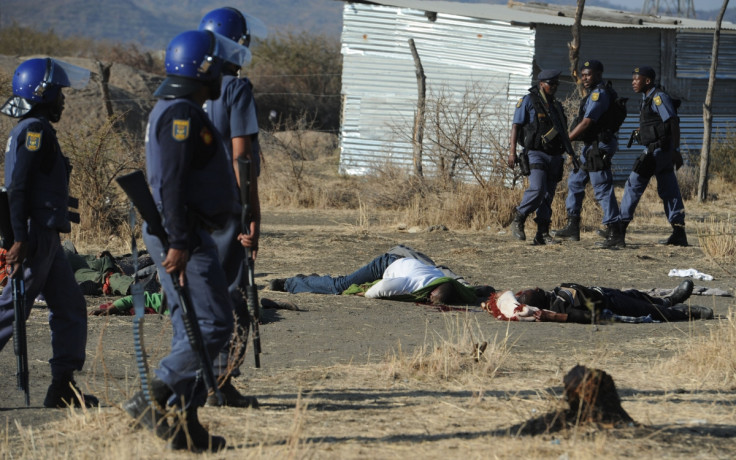 Police stand over the bodies of dead protesters in Marikana, 2012. (Getty)