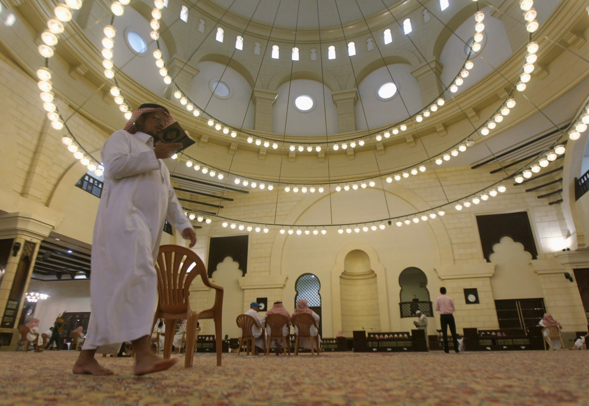 A Muslim man walks past as he reads the Koran at the Al-Rajhi mosque east of Riyadh