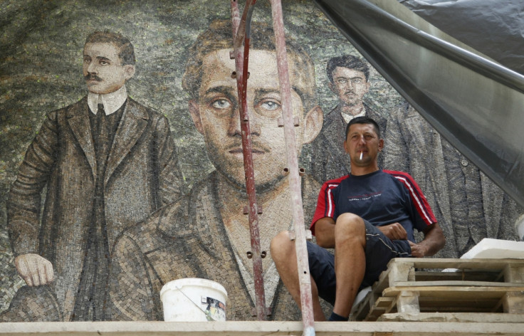 A worker smokes a cigarette in front of a mosaic with image of Gavrilo Princip, in Andricgrad village near Visegrad