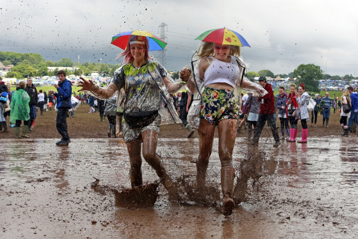 Happy despite the mud. Festival goers splash through puddles at the Glastonbury music festival Happy despite the mud. Festival goers splash through puddles at the Glastonbury music festival