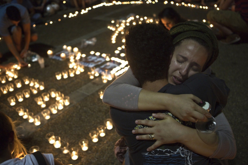 sraeli women hug each other as people light candles in Tel Aviv's Rabin Square as they mourn the death of three teenagers who were abducted,