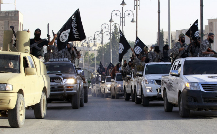 Islamic State fighters parade on military vehicles along the streets of a northern Raqqa province in Syria