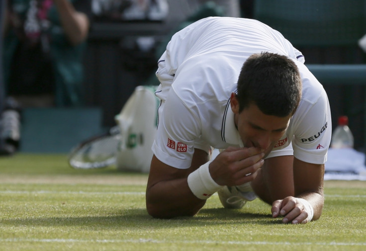 Novak Djokovic of Serbia eats some grass after defeating Roger Federer of Switzerland in their men's singles final tennis match at the Wimbledon Tennis Championships, in London July 6, 2014.