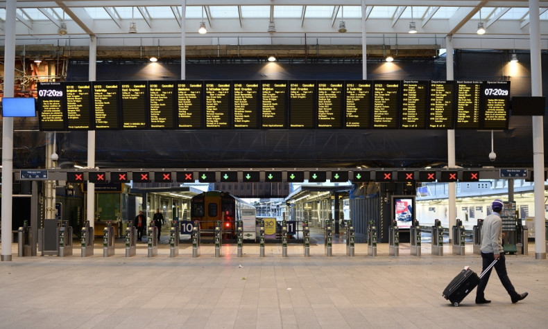 A lone commuter walks past the notice board at London Bridge Station showing all trains cancelled during rush hour in London