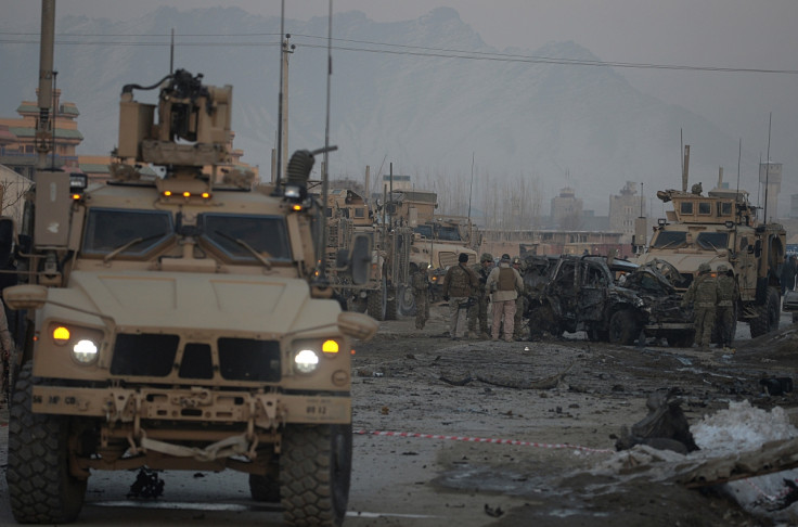 US soldiers examine a damaged vehicle at the site of a car bomb in Kabul