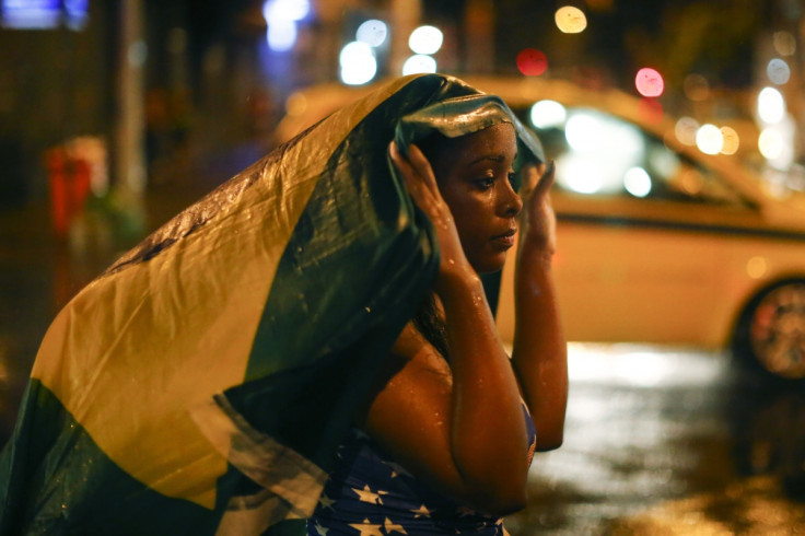 Drowning in tears: A Brazil fan walks in the rain after watching a broadcast of her team's loss against Germany