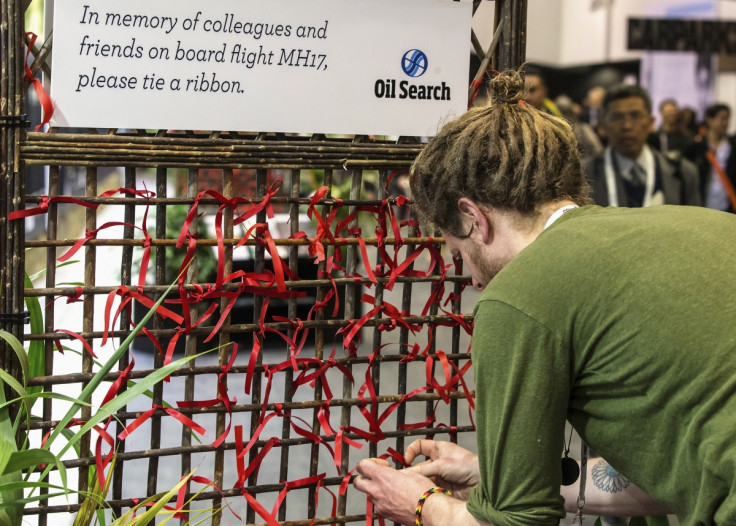 A delegate of the 20th International AIDS Conference ties a red ribbon to a memorial board as a tribute to colleagues killed in the Malaysia Airlines flight MH17, in Melbourne July 20, 2014 .