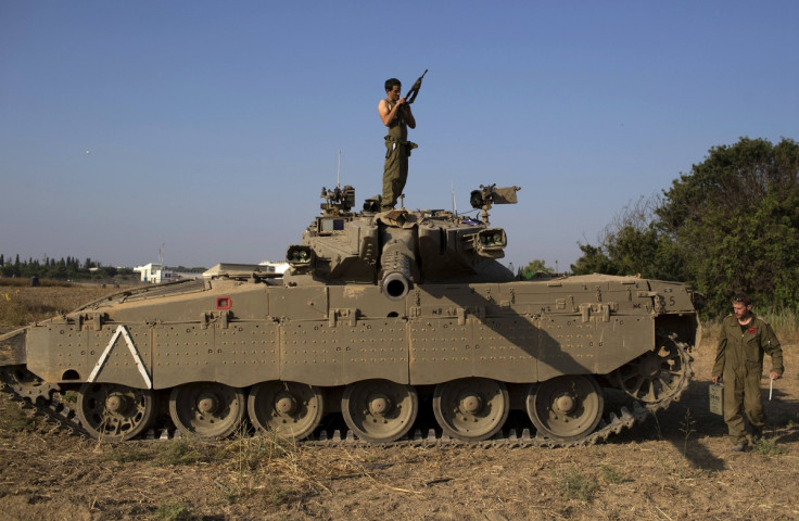 Israeli solider checks his weapon atop of a tank