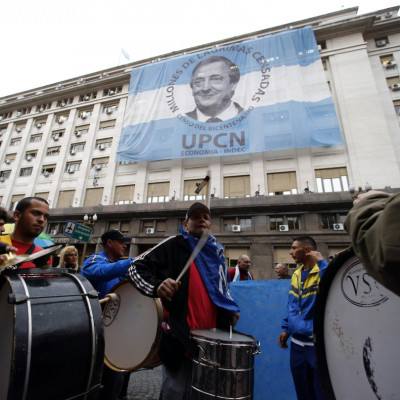 Pro-government demonstrators beat drums in front of an image of late President Nestor Kirchner placed over the Economy Ministry in Buenos Aires' financial district