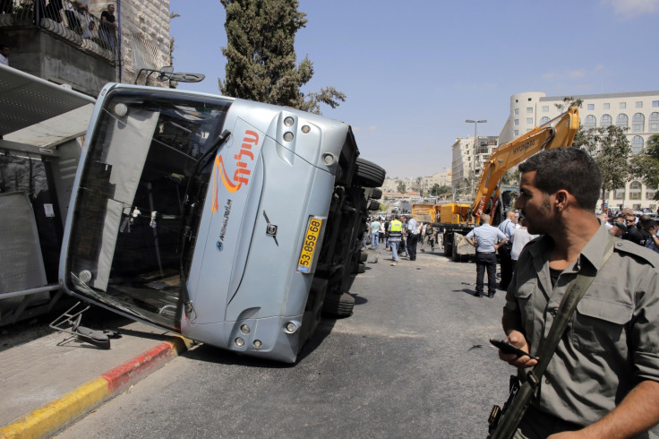 An Israeli border policeman looks at an overturned bus at the scene of a suspected attack in Jerusalem