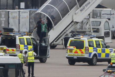 A man is escorted off a Qatar Airways aircraft by police at Manchester airport in Manchester, northern England August 5, 2014. A British fighter jet escorted a passenger plane into Manchester airport on Tuesday afterthe pilot reported that a suspect devic