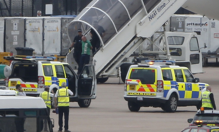A man is escorted off a Qatar Airways aircraft by police at Manchester airport in Manchester, northern England August 5, 2014. A British fighter jet escorted a passenger plane into Manchester airport on Tuesday afterthe pilot reported that a suspect devic