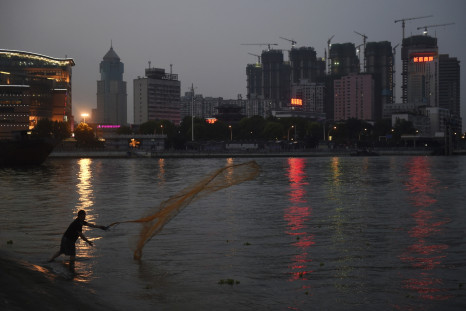A man casts a net by the side of a river next to a construction site of new residential buildings in Wuhan, Hubei province.