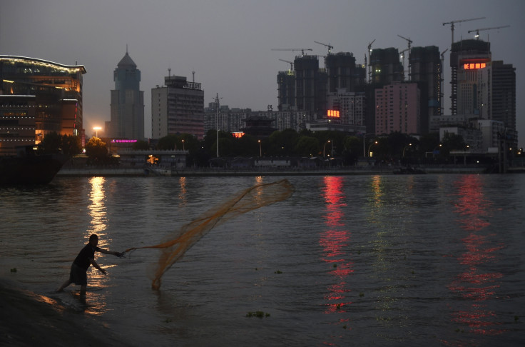 A man casts a net by the side of a river next to a construction site of new residential buildings in Wuhan, Hubei province.