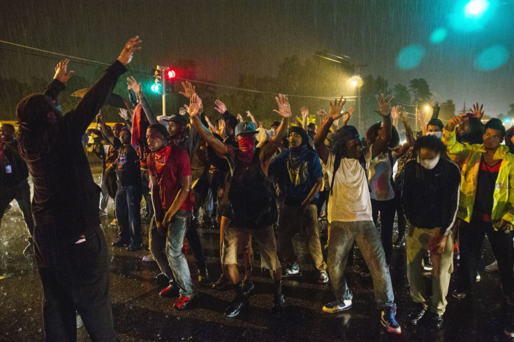 Protesters defying a curfew on the streets of Ferguson, Missouri, raise their arms in the gesture they claim teenager Michael Brown made before being shot dead by police. (Reuters)