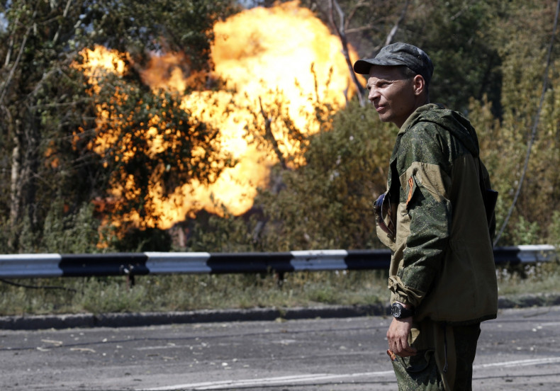 An armed pro-Russian separatist looks as flames erupt from a gas pipeline after a shelling in Donetsk