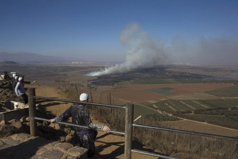 Druze men look at smoke rising on the Israeli-controlled side of the line dividing the Israeli-occupied Golan Heights from Syria following fighting near the Quneitra border crossing