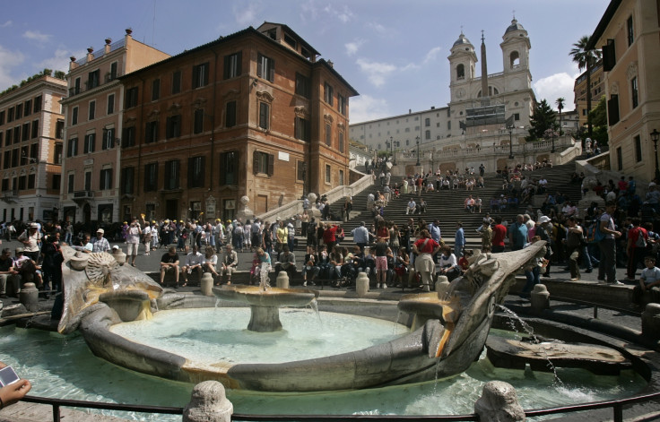 Tourists crowd about the famed Fontana della Barcaccia (Fountain of the Old Boat) at the foot of the Spanish Steps in Rome