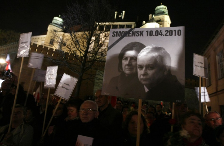 People hold a picture of late Polish President Kaczynski and his wife Maria during an event commemorating the first year anniversary of their funeral in downtown Krakow