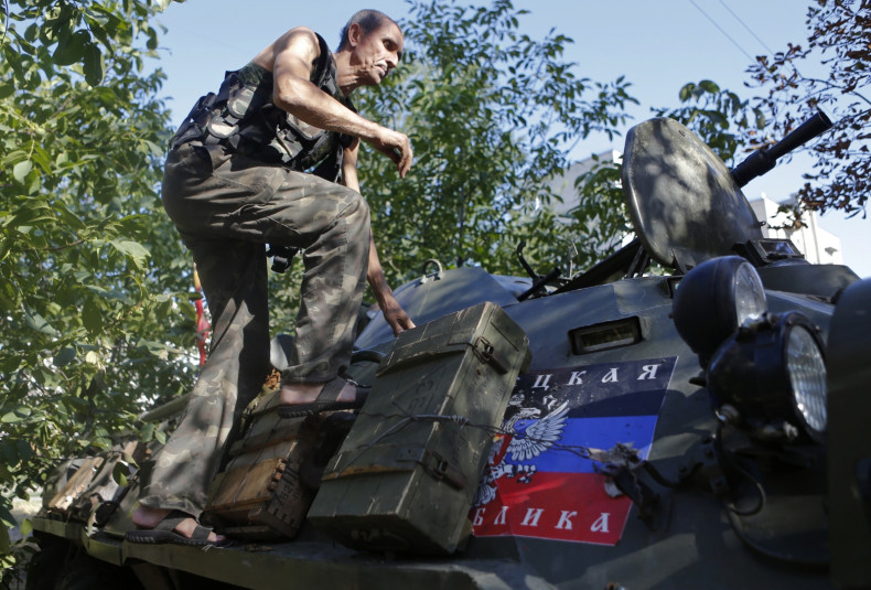 A pro-Russian separatist climbs atop an armoured personnel carrier as he guards a position in the eastern Ukrainian town of Ilovaysk