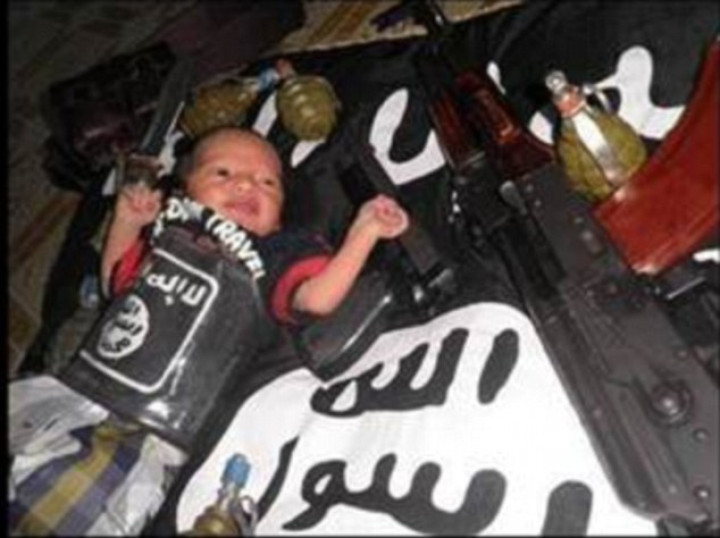 Photo showing baby surrounded by guns and grenades while wrapped in the black flag of IS Photo showing baby surrounded by guns and grenades while wrapped in the black flag of IS