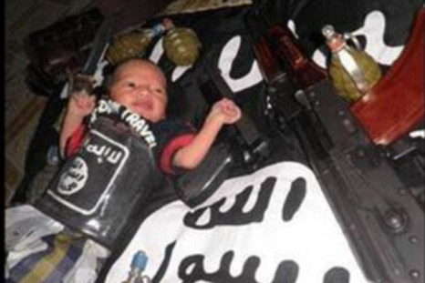 Photo showing baby surrounded by guns and grenades while wrapped in the black flag of IS