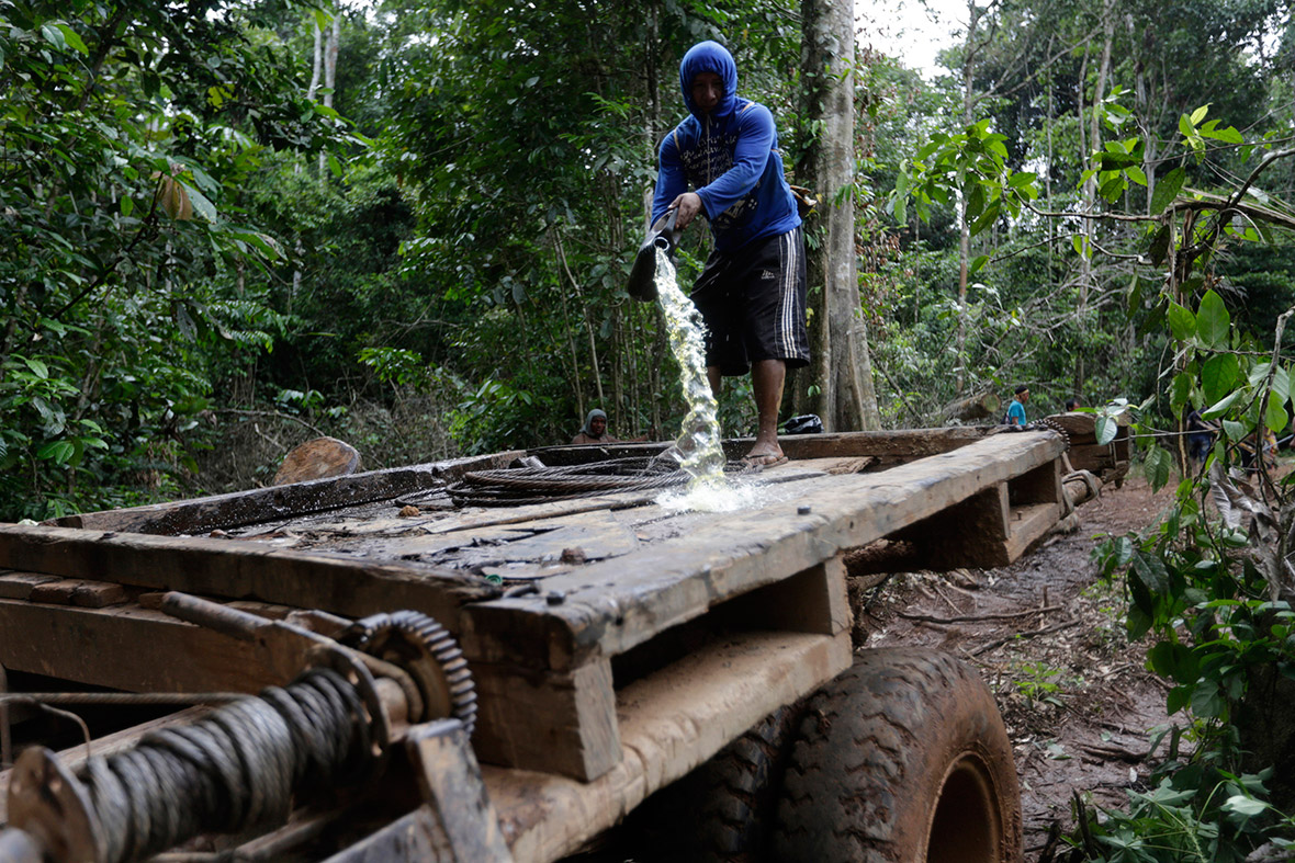 A Ka'apor man pours petrol on a logging truck in the Amazon