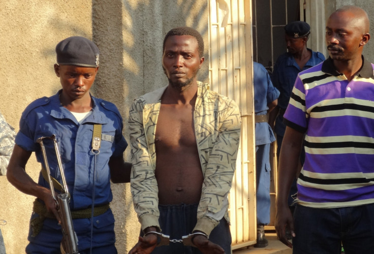 A Burundian policeman escorts suspect Christian Claude Butoyi (C) after he was arrested in Bujumbura for the murder of three Italian nun
