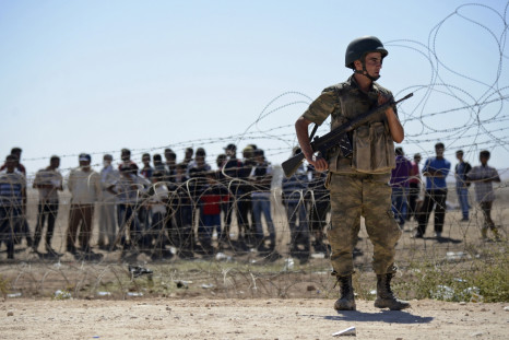 A Turkish soldier stands guard as Syrian Kurds wait behind the border fence near the southeastern town of Suruc in Sanliurfa province,