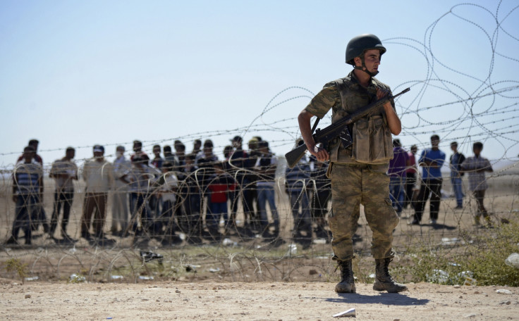 A Turkish soldier stands guard as Syrian Kurds wait behind the border fence near the southeastern town of Suruc in Sanliurfa province,
