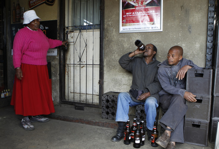 A woman looks on as men drink beer at a sheeben (bar) in Soweto, southwest of Johannesburg August 8, 2012