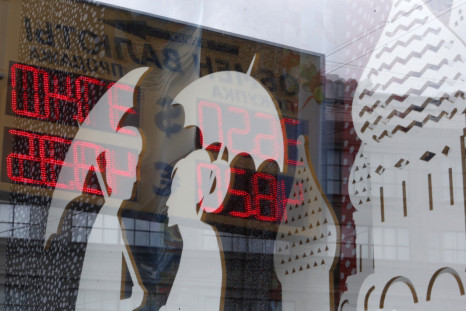 A board displaying currency exchange rates is reflected in a shop window in central Moscow