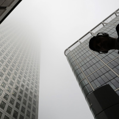 A man walks past a building in the morning mist at London's financial district of Canary Wharf September 16, 2014