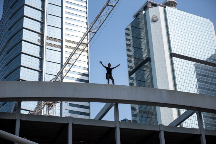 A man standing on top of a bridge overlooking a pro-democracy protest area threatens to jump