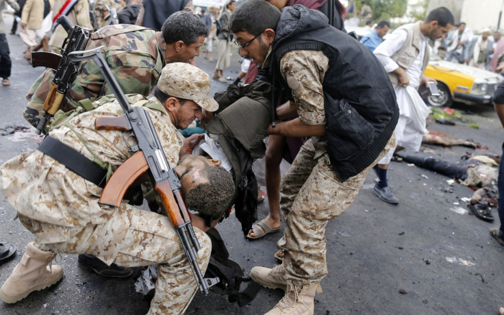 Shi'ite Houthi rebels carry a dead man at the scene of a suicide attack in Sanaa