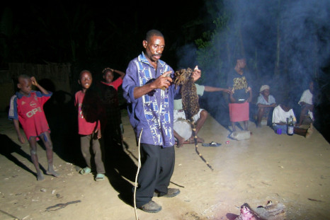 A African sorcerer performs a dance in front of a sacred fire