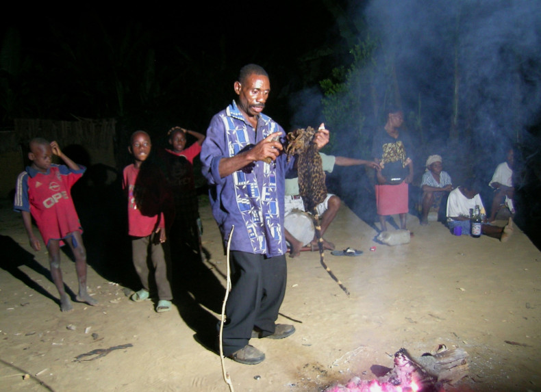 A African sorcerer performs a dance in front of a sacred fire