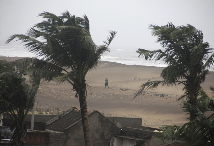 A man walks as strong winds blow along a beach in Gopalpur in the eastern Indian state of Odisha on 12 October 2014
