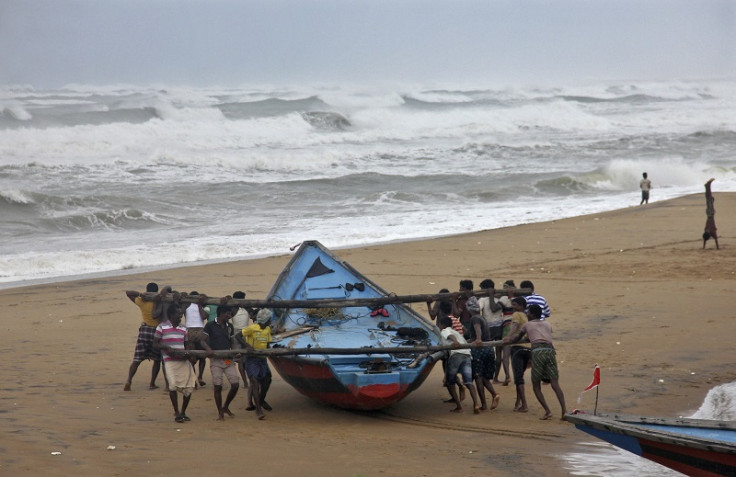 Fishermen move a fishing boat to a safer place along the shore as Cyclone Hudhud approaches