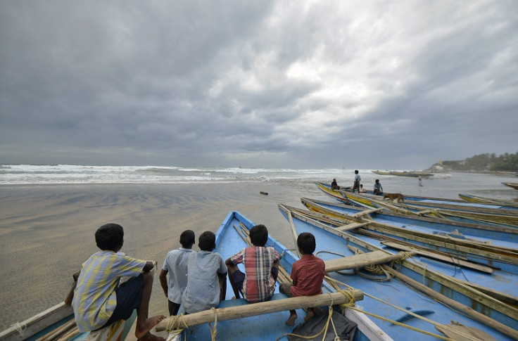 Children sit on fishing boats by the shore before being evacuated at Visakhapatnam district in the southern Indian state of Andhra Pradesh
