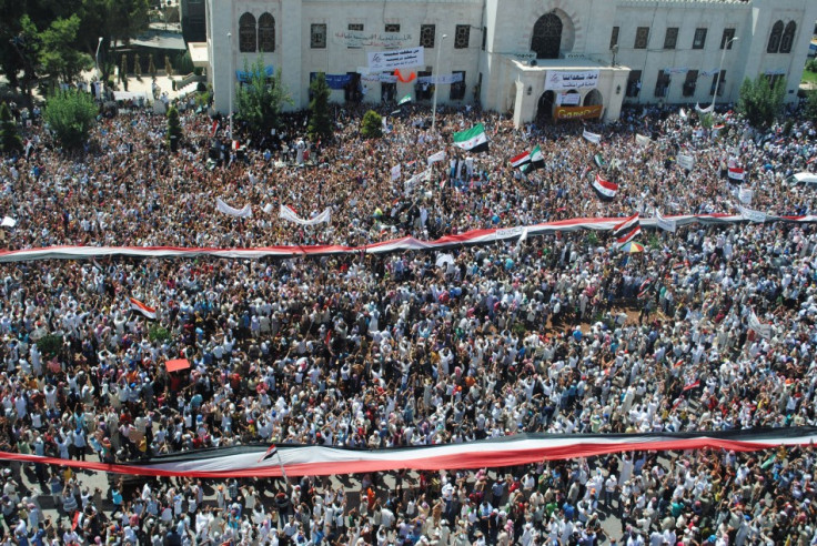 People hold a giant Syrian flag during a protest against President Bashar al-Assad in the city centre of Hama