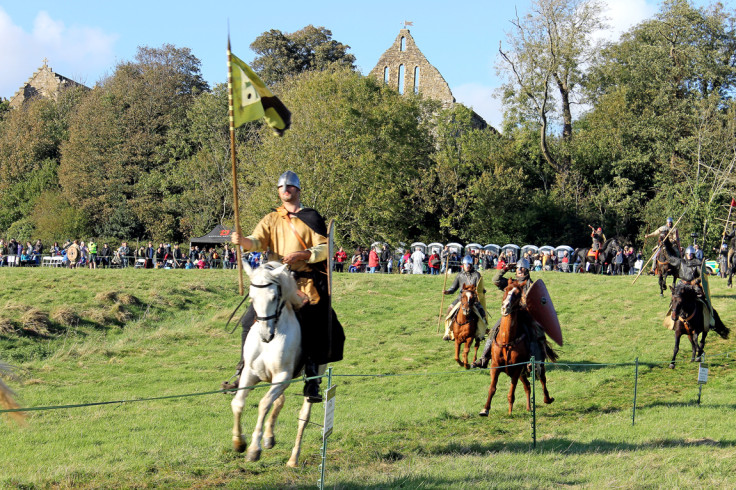 Norman knights carrying banners representing the Dukes of Normandy ride down the field during the re-enactment