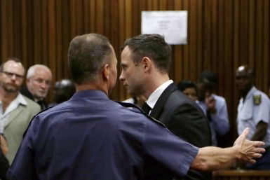 Oscar Pistorius led away to a cell by  a court guard after he was jailed for five years