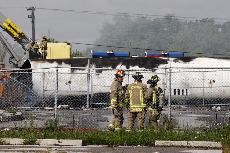 Canadian firefighters stand in front of an exploded propane tank