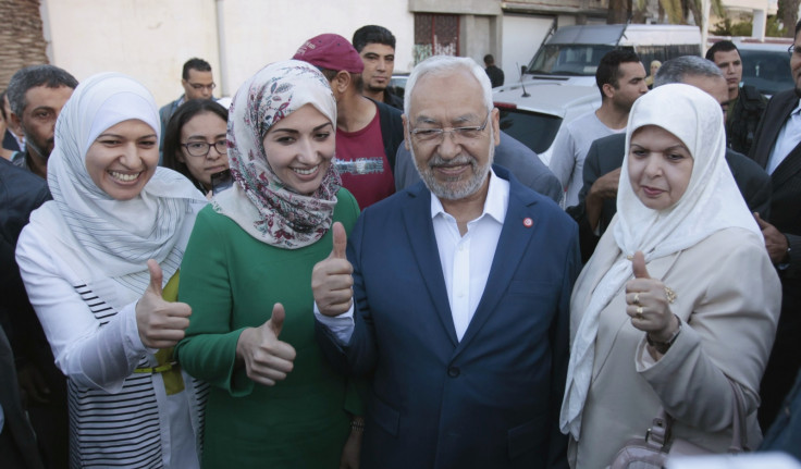 Rached Ghannouchi (C), leader of the Tunisian Islamist party Ennahda, gestures with his wife and two daughters Yousra (L) and Soumaya (2nd L) at a polling station during an election in Tunisia