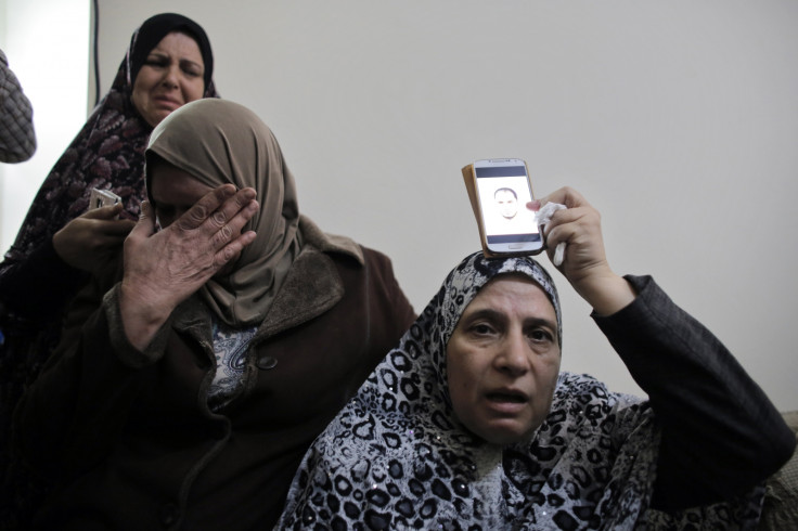 The mother of Palestinian Moataz Hejazi (R) holds a picture of him over a phone over her head at the family house in the Abu Tor neighbourhood of east Jerusalem