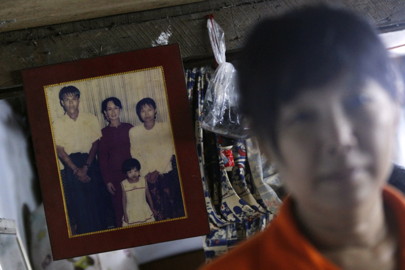 Than Dar, the wife of slain journalist Par Gyi, stands in front of a family photograph showing herself, her husband and daughter posing with Aung San Suu Kyi, during a Reuters interview at her home in Yangon